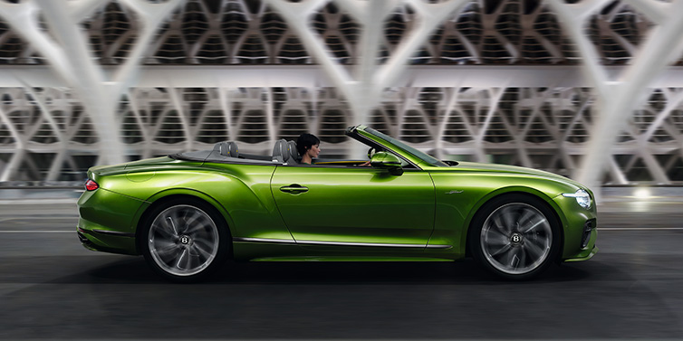 Bentley Al Khobar Bentley Continental GTC Speed convertible side profile in Tourmaline Green paint driving dynamically on a bridge at night