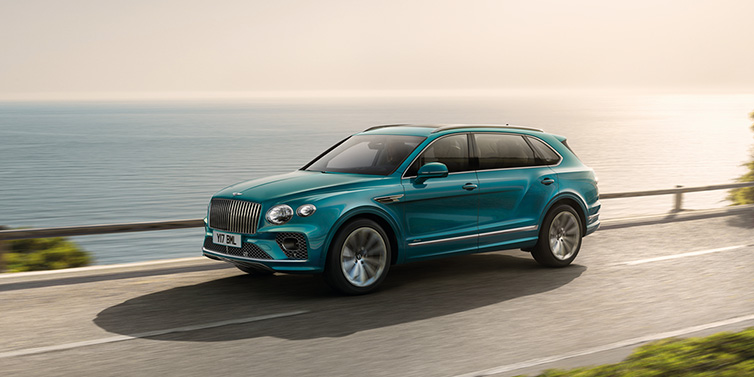 Bentley Al Khobar Bentley Bentayga Extended Wheelbase Azure SUV in Topaz blue paint driving dynamically by the ocean