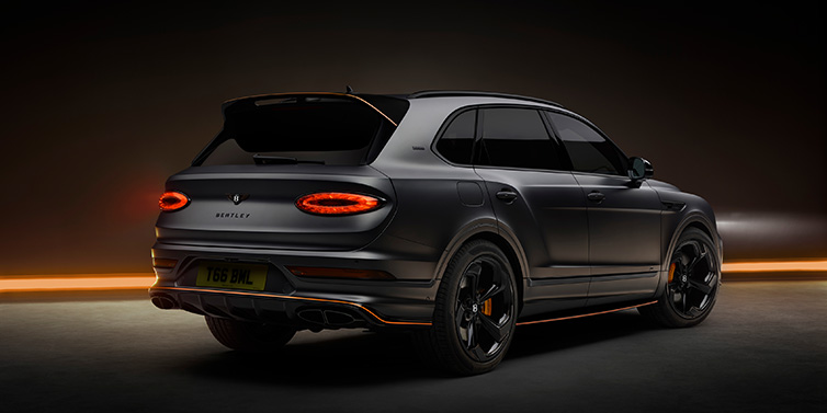 Bentley Al Khobar Bentley Bentayga S Black Edition SUV rear three quarter in Anthracite Satin paint against a dark red and yellow background