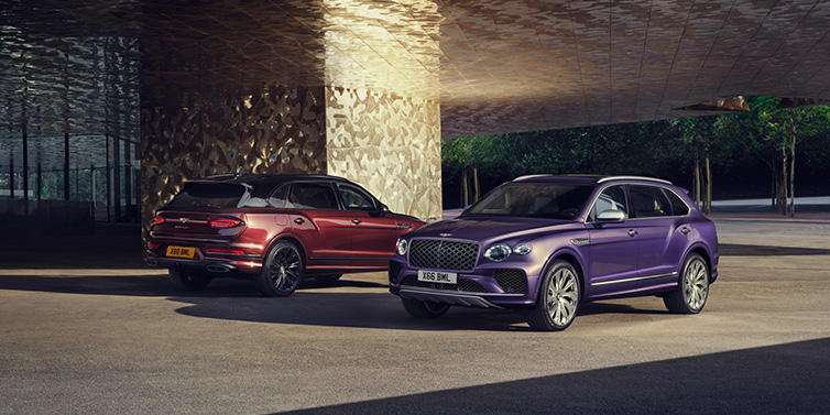 Bentley Al Khobar A duo of Bentley Bentayga Extended Wheelbase Mulliner SUVs parked in a city environment, with Tanzanite Purple and Cricket Ball red exterior paint