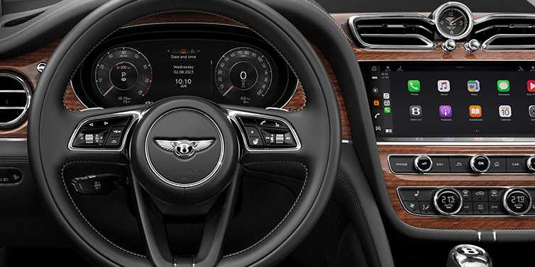 Bentley Al Khobar Bentley Bentayga SUV front interior detail of steering wheel and driver screens surrounded by Beluga black hide and Crown Cut Walnut veneer