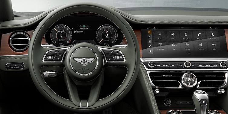 Bentley Al Khobar New Bentley Flying Spur front cabin interior in Cumbrian green hide with Crown Cut walnut veneer showing steering wheel and driver controls