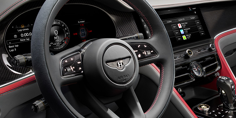 Bentley Al Khobar Bentley Flying Spur Speed sedan front interior detail showing steering wheel and driver screens surrounded with Hotspur red and Gravity Grey hides